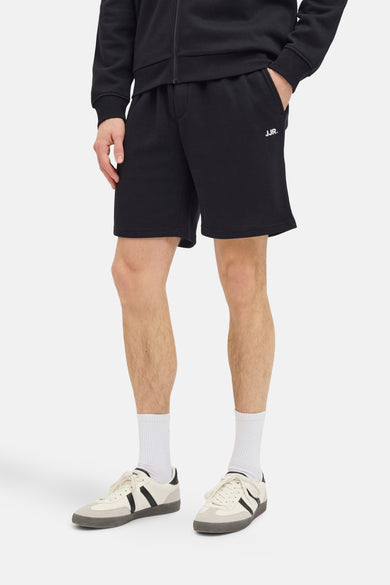 Zwarte short van JJREBEL, met een relaxte pasvorm, gecombineerd met witte sokken en crèmekleurige sneakers.