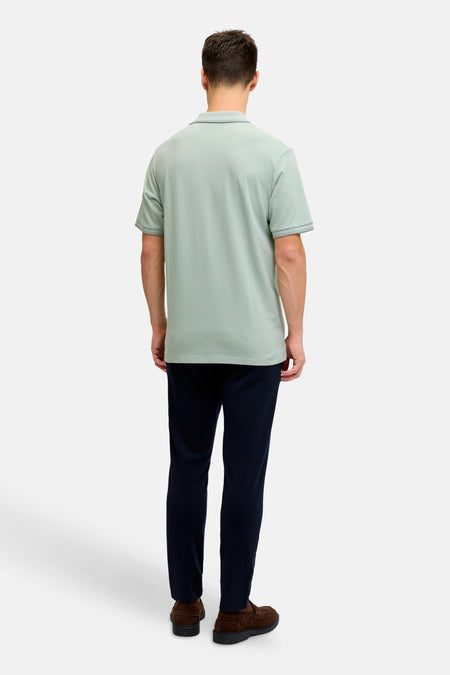 Polo verte JJREBEL verte de couleur verte à manches courtes et col, portée par un homme avec un pantalon bleu foncé et des mocassins marron, vue de dos.