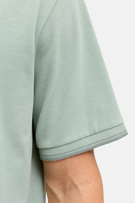 Polo verte JJREBEL de couleur verte en piqué avec un ourlet de manche côtelé, gros plan du côté.
