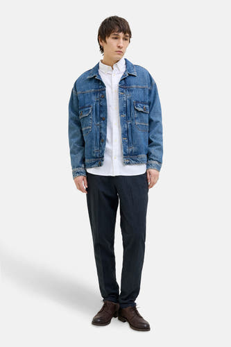 Blauwe chino van JACK & JONES JEANS INTELLIGENCE, gecombineerd met een wit overhemd, denim jack en bruine schoenen.
