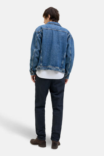 Blauwe chino van JACK & JONES JEANS INTELLIGENCE, gecombineerd met een spijkerjack, een wit T-shirt en bruine schoenen.