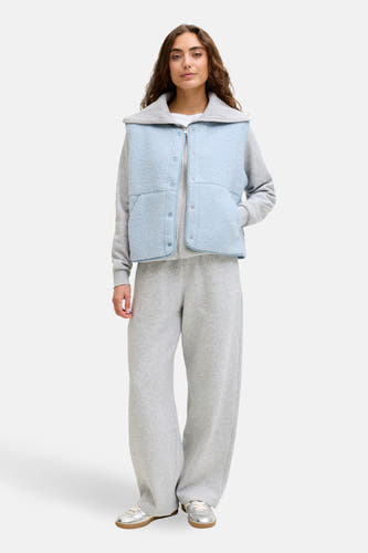 Gilet bleu de JJXX, porté sur un pull gris et un pantalon de jogging large.