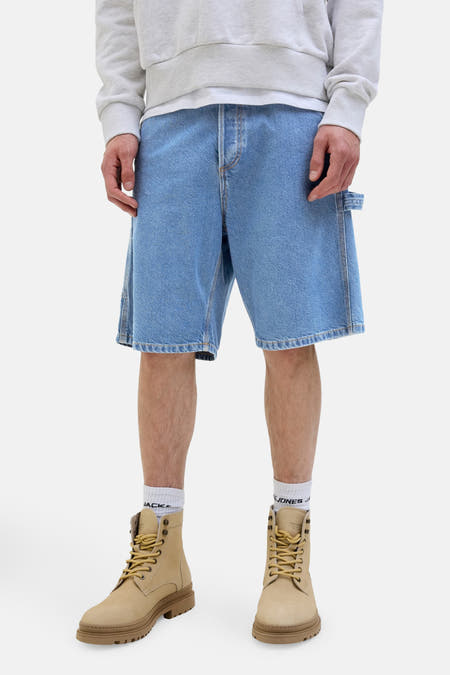 Jeansshort van lichtblauw denim van JACK & JONES JEANS INTELLIGENCE, met worker details en gecombineerd met laarzen en sokken.
