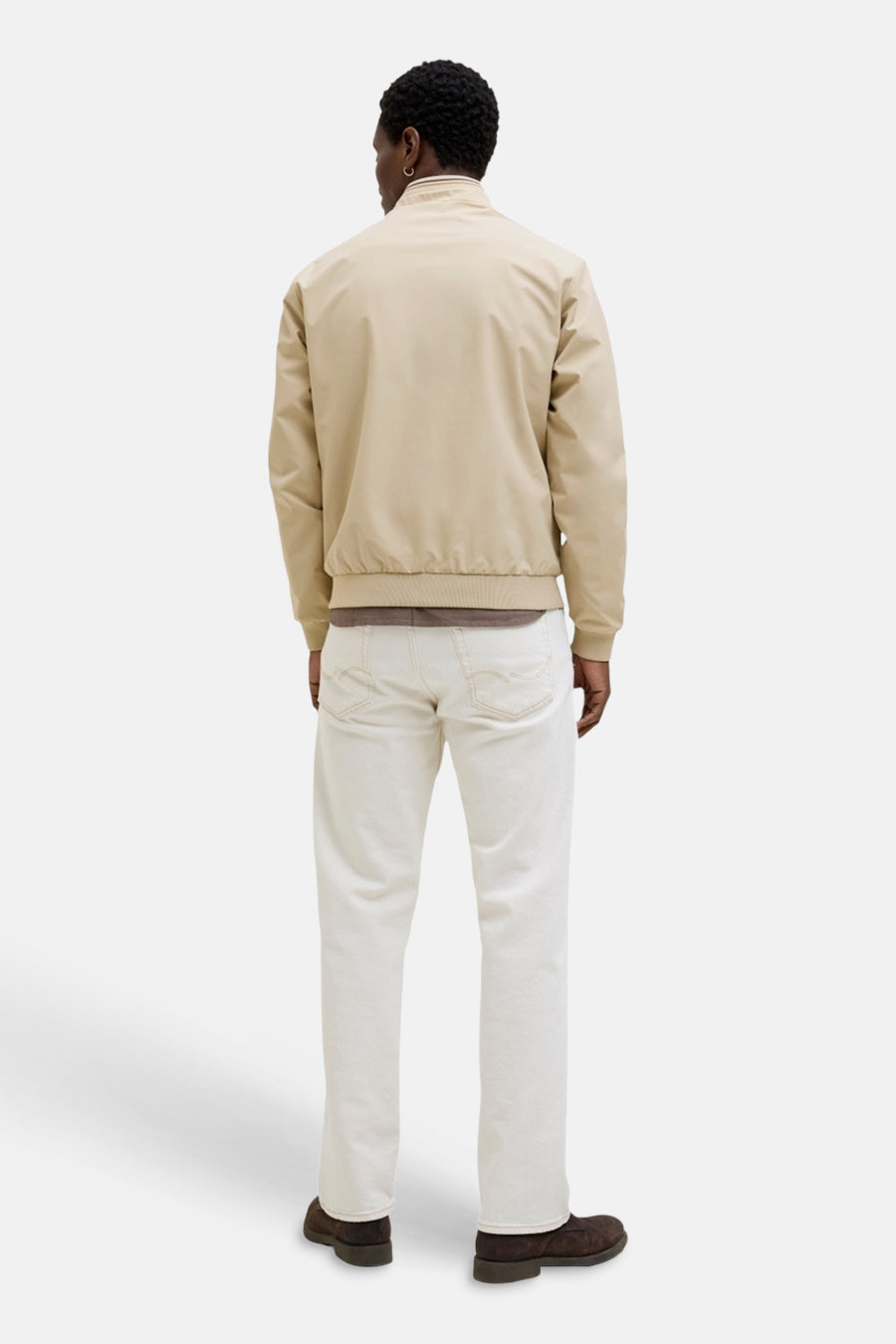 Beige korte jas van PREMIUM by JACK & JONES, rugzicht, met geribbelde boorden en kraag, gedragen door een man over een bruin shirt met witte jeans en donkerbruine schoenen.
