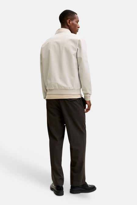 Veste courte beige de PREMIUM by JACK & JONES avec ourlet et poignets côtelés, dos, portée avec un pantalon foncé et des chaussures noires.