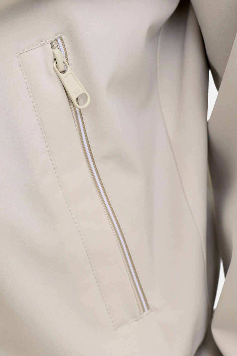 Beige korte jas van PREMIUM by JACK & JONES met een deels open rits met streepmotief en een logodetail op de ritssluiting.