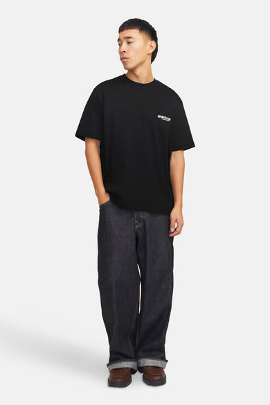 Zwart T-shirt met korte mouwen van CORE BY JACK & JONES, gedragen met wijde jeans en bruine schoenen.