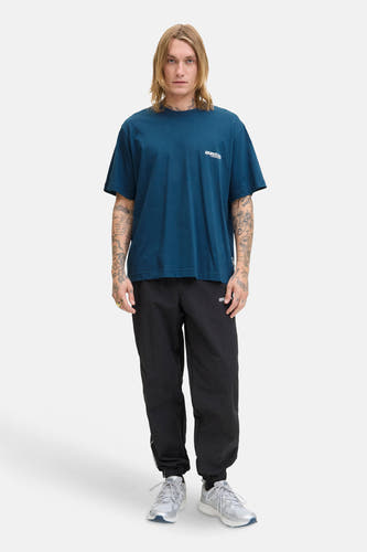 Blauw T-shirt met korte mouwen van CORE BY JACK & JONES, met logo, gedragen met zwarte trainingsbroek en zilveren sneakers.