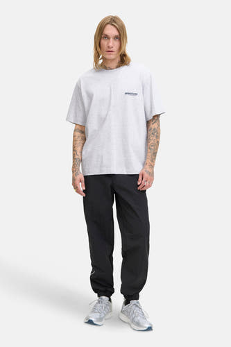 Grijs T-shirt met korte mouwen van CORE BY JACK & JONES, met een klein logo op de borst, gedragen met zwarte broek en sneakers.
