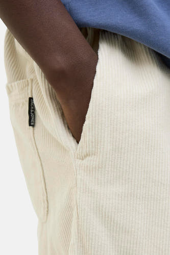 Ecru short van JACK & JONES JEANS INTELLIGENCE, met steekzak en donkere huid die in de zak steekt.