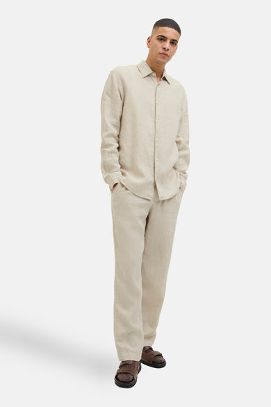 Chemise beige à longues manches de PREMIUM by JACK & JONES, portée avec un pantalon et des sandales.