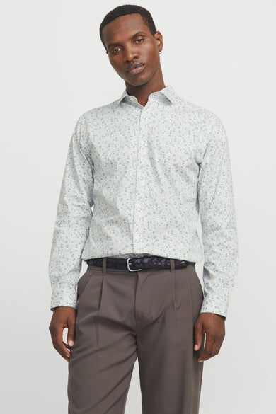 Chemise blanche à manches longues de PREMIUM by JACK & JONES, imprimée de fleurs, associée à un pantalon gris et une ceinture tressée.
