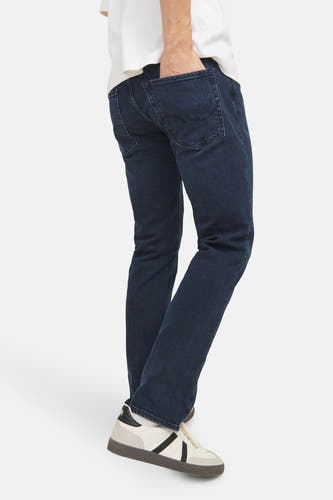 Jean bleu marine droit de JACK & JONES JEANS INTELLIGENCE, avec une main dans la poche arrière, associé à des sneakers blanches.
