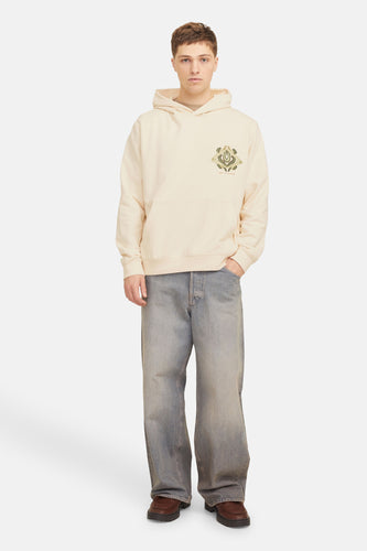 Ecru sweater met kap van ORIGINALS BY JACK & JONES, met geborduurde grafische details op de borst, gecombineerd met wijde jeans en bruine schoenen.
