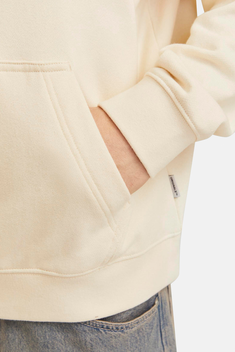 Ecru sweater met kap van ORIGINALS BY JACK & JONES, met een hand in de zak, en een label aan de zijkant.