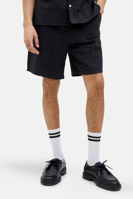 Zwarte shorts van ORIGINALS BY JACK & JONES, met een losse pasvorm en gedragen met witte sokken en zwarte schoenen.