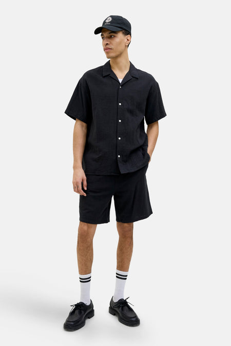 Zwarte shorts van ORIGINALS BY JACK & JONES, gecombineerd met witte sokken met strepen en zwarte schoenen.