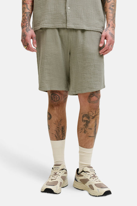 Groene short van ORIGINALS BY JACK & JONES, met een gekreukelde textuur, gedragen met crèmekleurige sokken en retro-stijl sneakers.