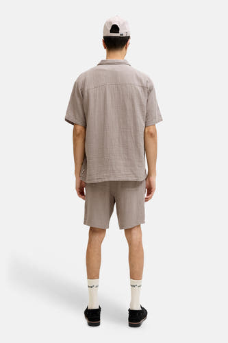 Bruine short van ORIGINALS BY JACK & JONES, met een geruit patroon, gecombineerd met witte sokken en zwarte schoenen, gezien van achteren.

