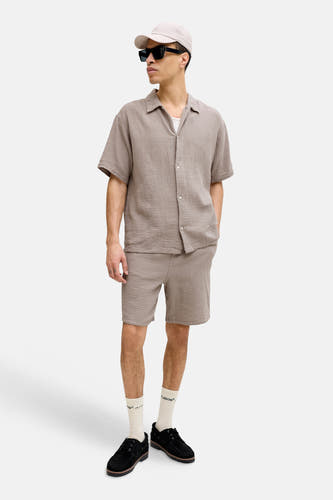 Bruine short van ORIGINALS BY JACK & JONES, gecombineerd met een bruin hemd met korte mouwen en zwarte instappers.