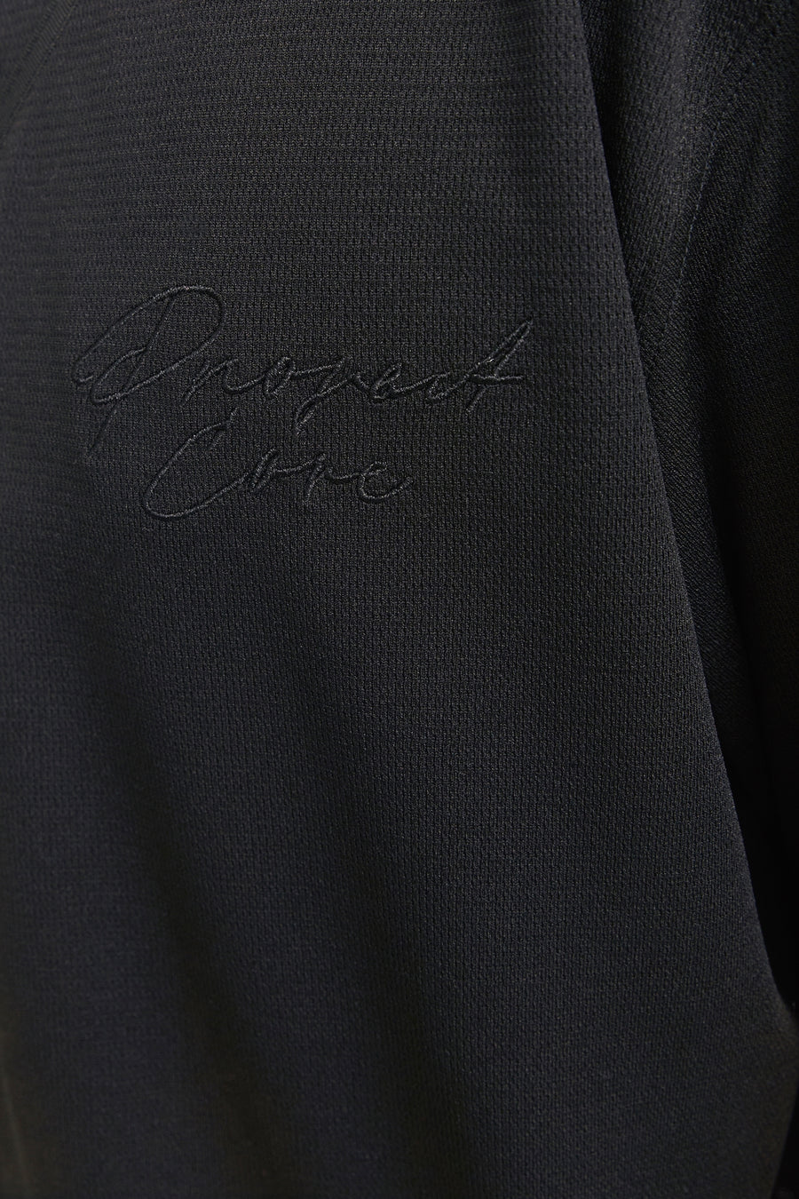 Zwart geborduurd logo op zwarte stoffen kleding.
