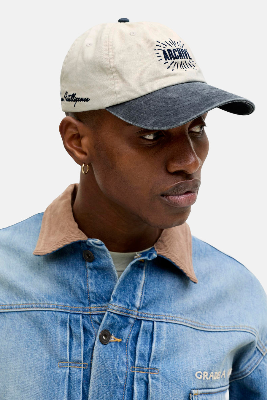Casquette beige de ACCESSORIES BY JACK & JONES avec visière gris foncé et inscription "Archive", portée avec une veste en jean à col marron.