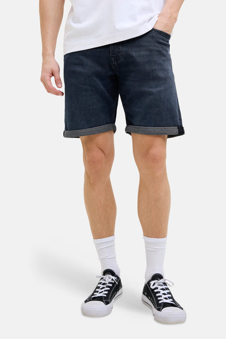 Donkerblauwe jeansshort van JACK & JONES JEANS INTELLIGENCE, met omgeslagen broekspijpen, gedragen met witte sokken en zwarte sneakers.