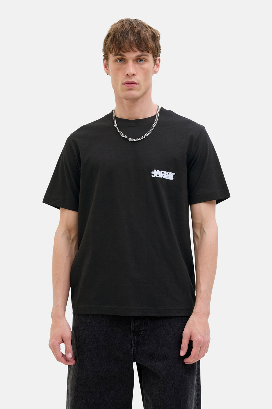 Zwart T-shirt met korte mouwen van CORE by JACK & JONES, met een kleine witte logo op de borst en een zilveren ketting.
