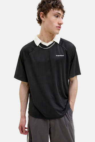 Polo noir à manches courtes de CORE BY JACK & JONES, avec col blanc et chaîne argentée.