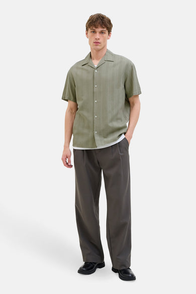 Chemise verte à manches courtes de PREMIUM BLUE par JACK & JONES, avec des rayures verticales, portée avec un chemis blanc et un pantalon.