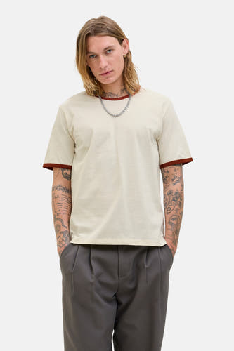 Ecru T-shirt met korte mouwen van ORIGINALS BY JACK & JONES, met bruine bies langs de hals en mouwen, gedragen met een zilverkleurige ketting.
