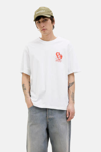 Wit T-shirt met korte mouwen van ORIGINALS BY JACK & JONES, met een oranje print op de borst en gecombineerd met een khaki pet en grijze jeans.
