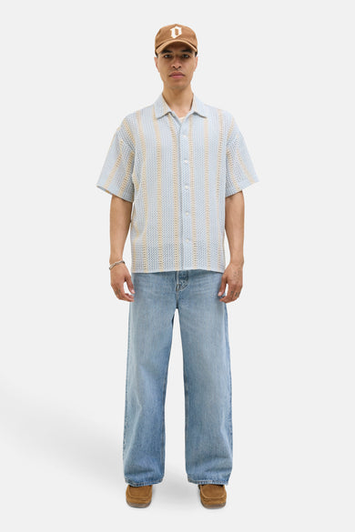 Lichtblauw hemd met korte mouwen van ORIGINALS BY JACK & JONES, met verticale strepen en gedragen met een pet, jeans en suède schoenen.