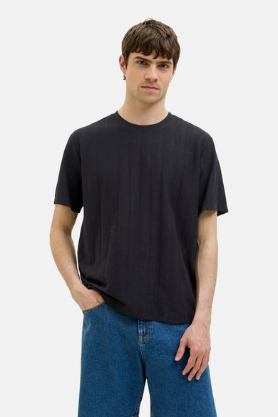 Zwart T-shirt met korte mouwen van JJREBEL, met een subtiele textuur en gedragen met blauwe jeans.

