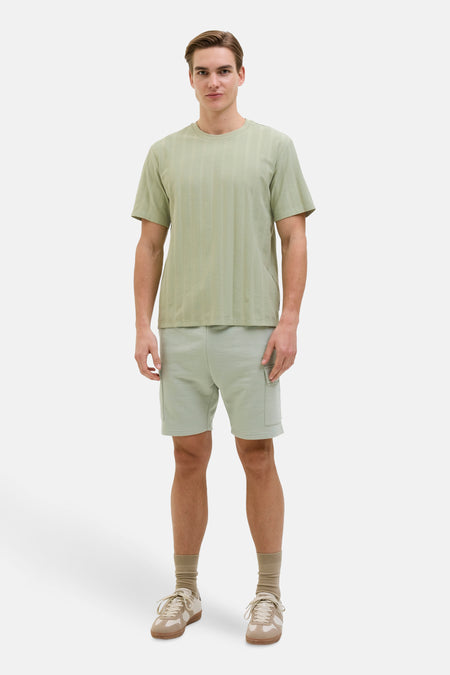 Groen T-shirt met korte mouwen van JJREBEL, met een subtiel verticaal streepjespatroon en gedragen met shorts en sneakers.