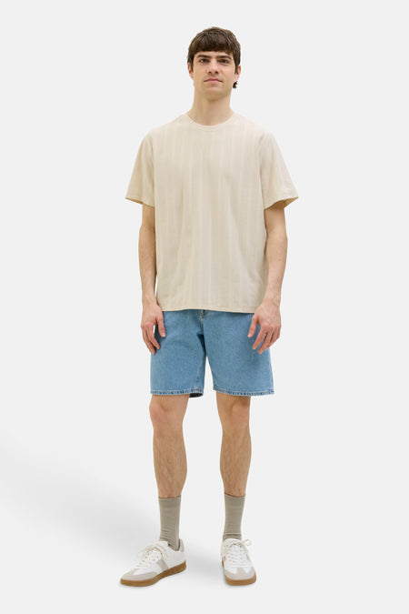 T-shirt beige à manches courtes de JJREBEL, avec des rayures verticales subtiles, associé à des shorts en denim, des chaussettes et des baskets.
