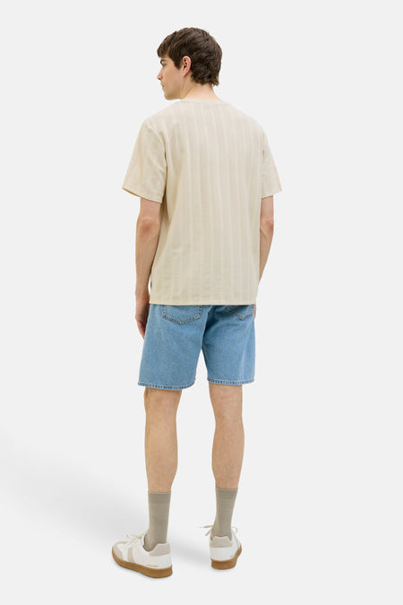 Beige T-shirt met korte mouwen van JJREBEL, met subtiele verticale strepen, gecombineerd met denim shorts en sneakers.
