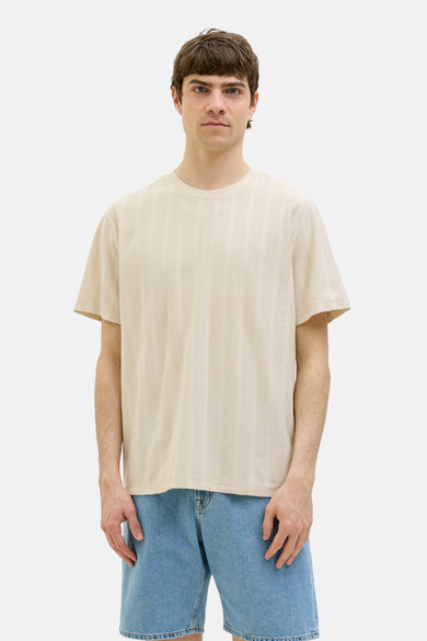 Beige T-shirt met korte mouwen van JJREBEL, met een verticaal gestreept patroon en gedragen met denim shorts.
