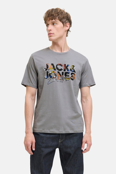 T-shirt gris à manches courtes d'ORIGINALS BY JACK & JONES, avec une impression colorée sur la poitrine, associé à des jeans foncés.