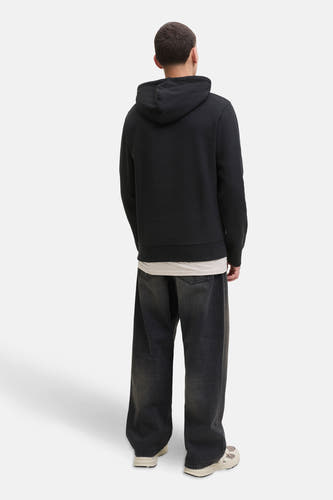 Zwarte sweater met kap van CORE BY JACK & JONES, met losse, donkergrijze jeans en crèmekleurige sneakers.