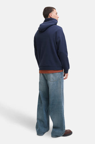 Pull-over bleu avec capuche de CORE BY JACK & JONES, porté avec un t-shirt marron et des jeans larges.