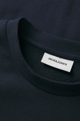 Blauwe sweater met ronde hals van CORE BY JACK & JONES, close-up van de kraag en label.
