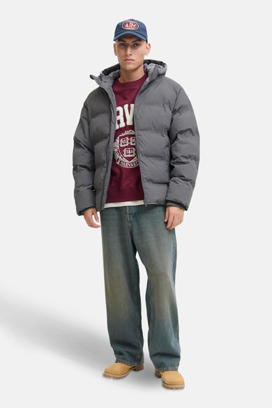 Grijze leren jas van ORIGINALS BY JACK & JONES, met een capuchon, gecombineerd met een bordeauxrode trui en blauwe jeans.
