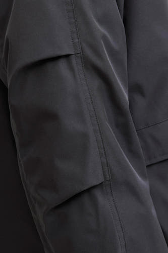 Zwarte korte jas van CORE BY JACK & JONES, detailopname van de mouw met zak en stiksels.