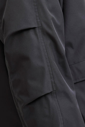 Zwarte korte jas van CORE BY JACK & JONES, detailopname van de mouw met zak en stiksels.