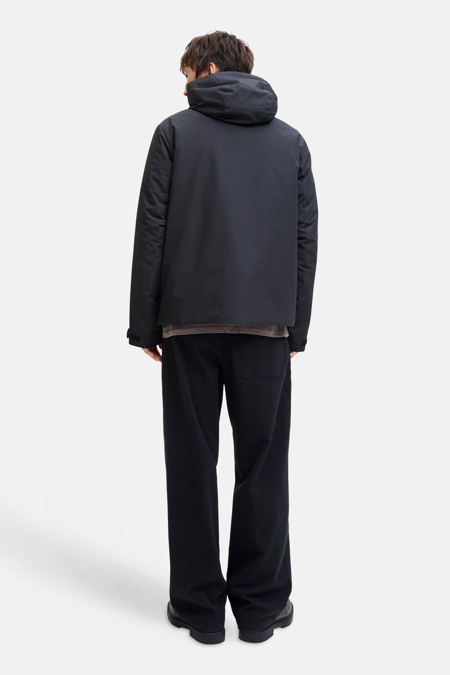 Zwarte korte jas van CORE BY JACK & JONES, gezien van achteren, met capuchon en zwarte broek.