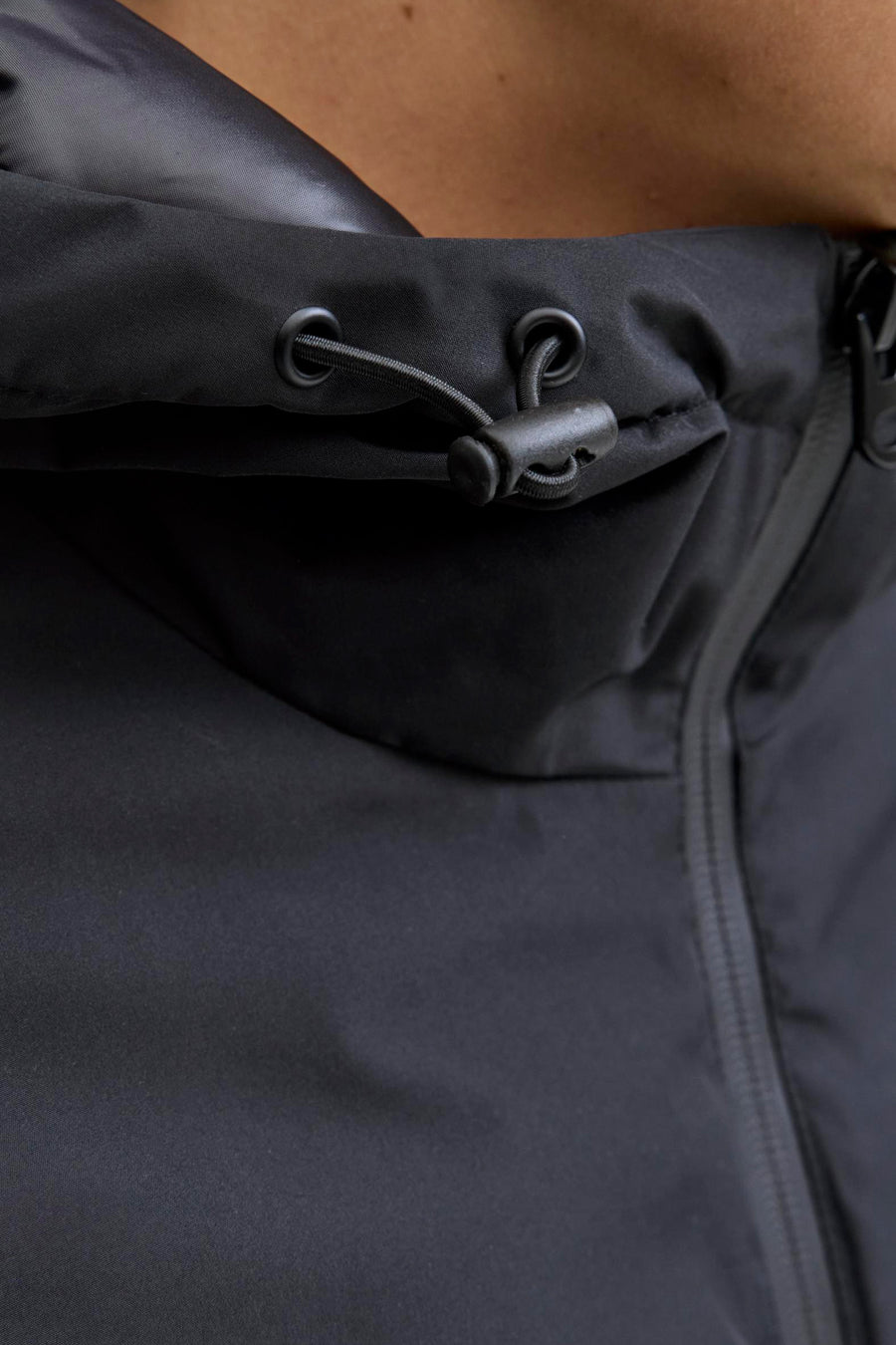 Zwarte korte jas van CORE BY JACK & JONES, close-up van de kraag met trekkoord en rits.