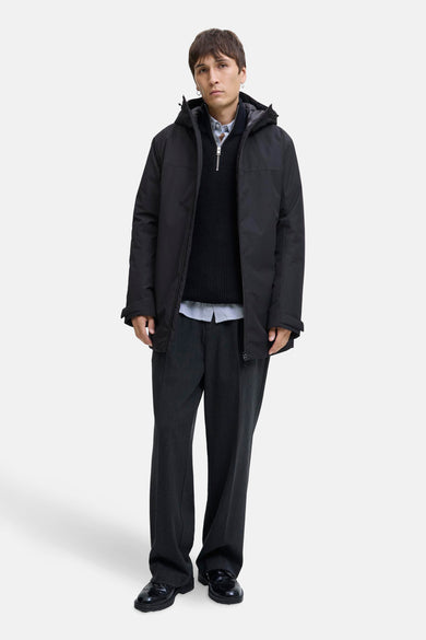 Zwarte jas van ORIGINALS BY JACK & JONES, met capuchon en over een trui en pantalon gedragen.