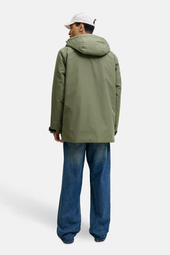 Groene korte jas van ORIGINALS BY JACK & JONES, met capuchon en gedragen met blauwe jeans en een witte pet, gezien van achteren.
