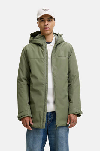 Groene korte jas van ORIGINALS BY JACK & JONES, met capuchon, over een gestreepte trui en blauwe jeans.
